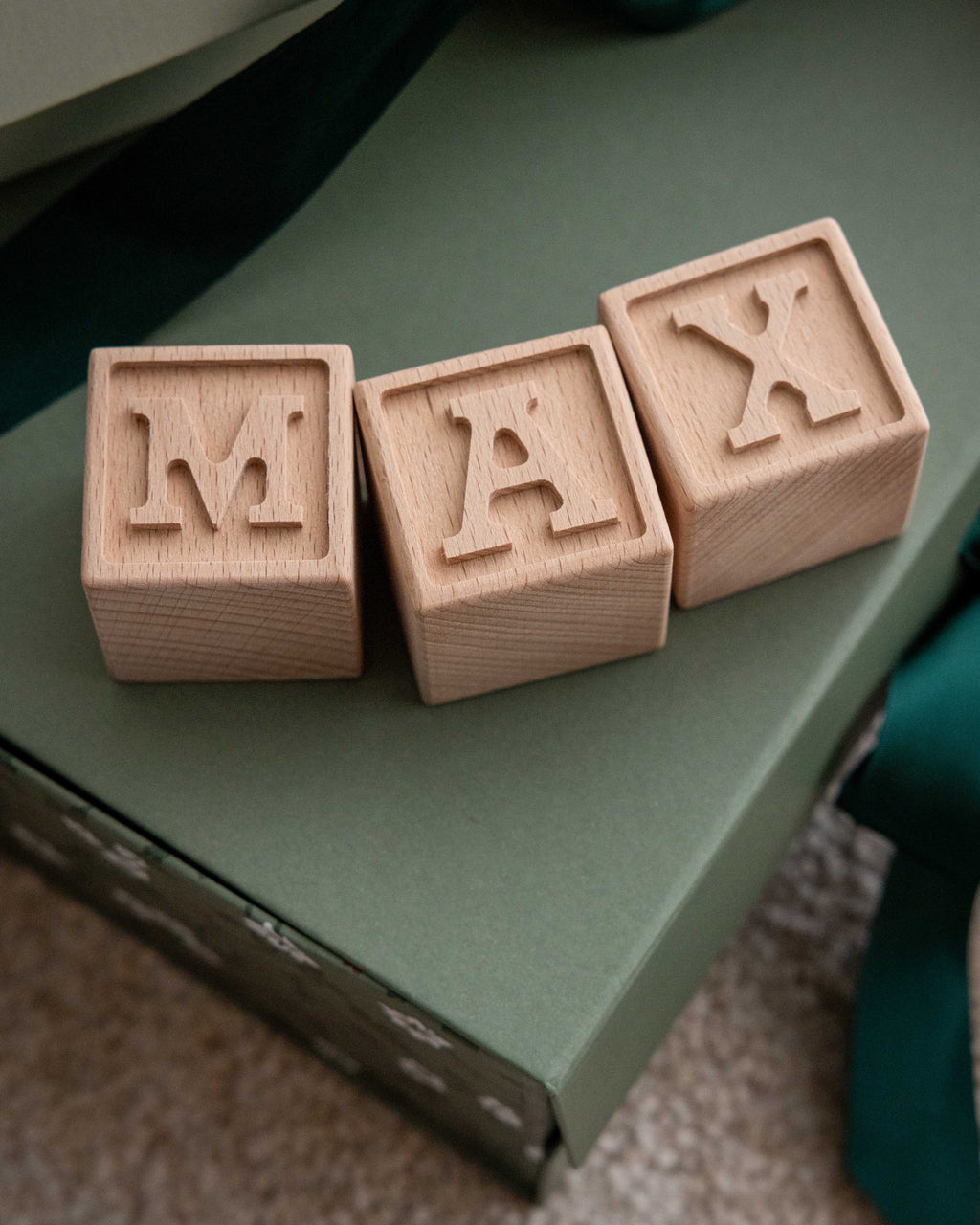 Bokstavsklossar i trä på grön aks som bildar namnet Max